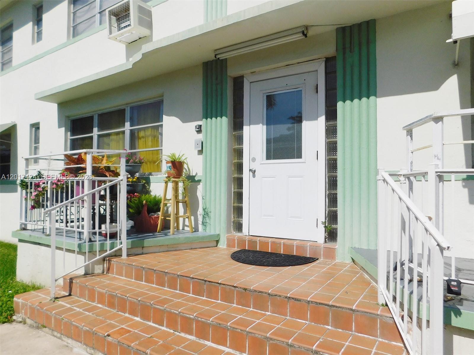 A white front door with a glass pane sits atop tiled steps at an entrance — 1735 Marseille Dr # 2, Miami Beach FL 33141, MIAMI BEACH, FL