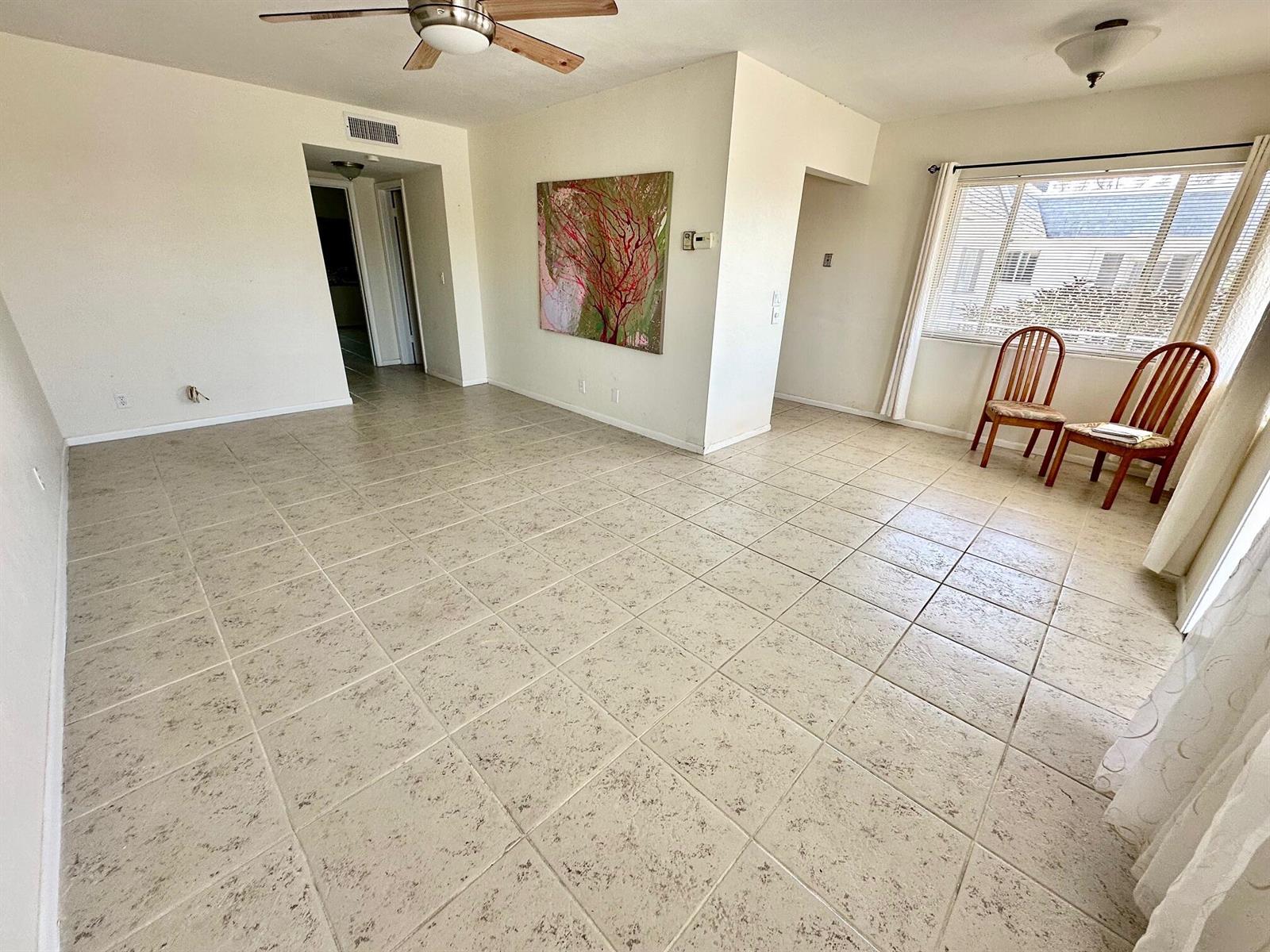 An empty room features light-colored tile flooring, a ceiling fan, and two wooden chairs — 2880 Lake Osborne Drive # 210, FL 33461, FL