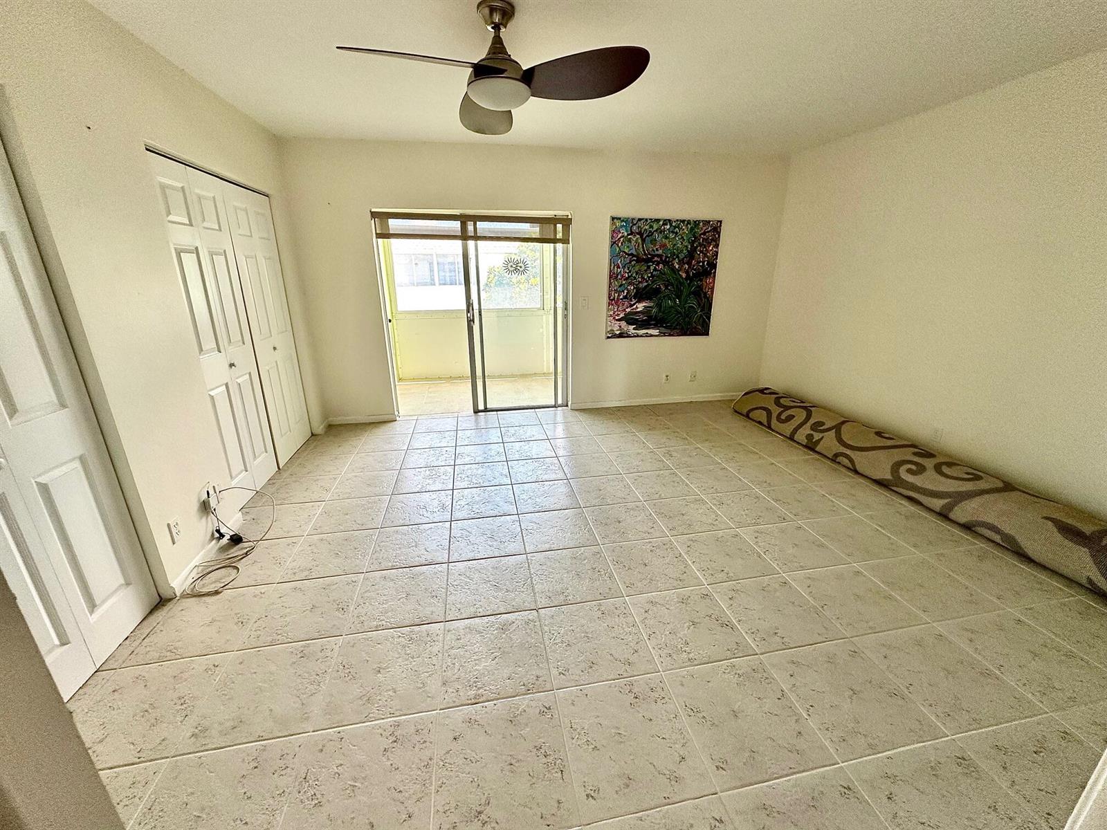 An empty room with light tile flooring, a ceiling fan, and a sliding glass door — 2880 Lake Osborne Drive # 210, FL 33461, FL