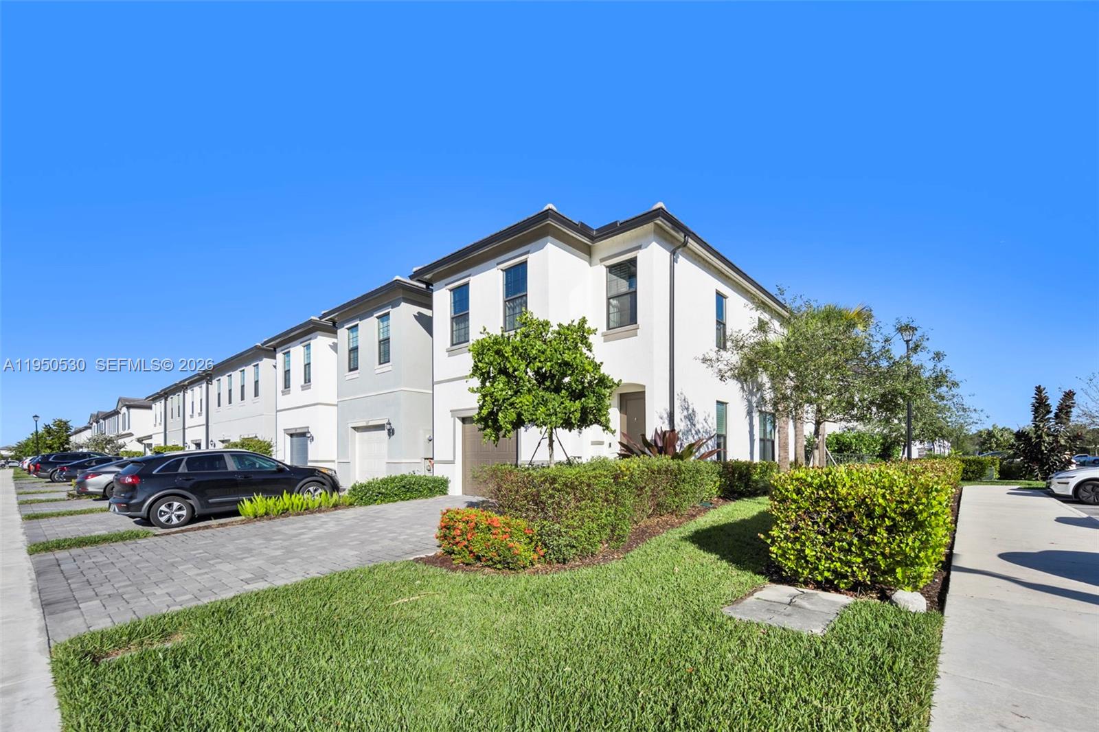 A row of modern two-story townhouses with paved driveways and manicured landscaping under a blue sky — 2121 S Appleton Cir S, Oakland Park FL 33309, OAKLAND PARK, FL