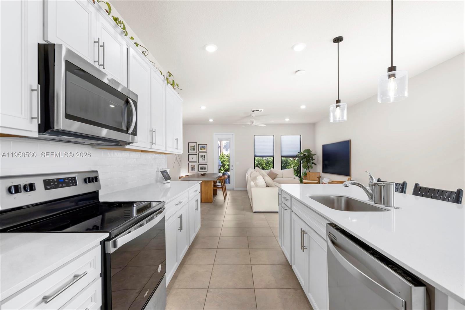 A modern kitchen with white cabinets and quartz countertops opens into a living room area — 2121 S Appleton Cir S, Oakland Park FL 33309, OAKLAND PARK, FL