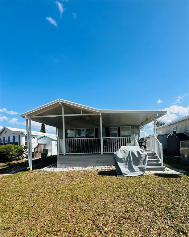 A mobile home features a large covered front porch with white railings and stairs — 627 ARNOLD PALMER DRIVE, DAVENPORT, FL