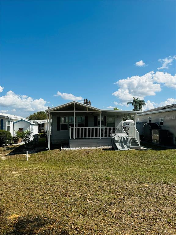 The exterior of a manufactured home features a covered porch with white railings and stairs — 627 ARNOLD PALMER DRIVE, DAVENPORT, FL