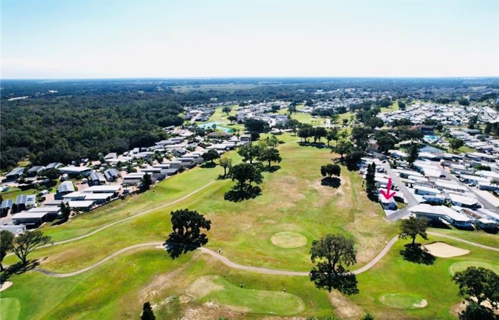 An aerial view shows a mobile home community situated alongside a golf course — 627 ARNOLD PALMER DRIVE, DAVENPORT, FL