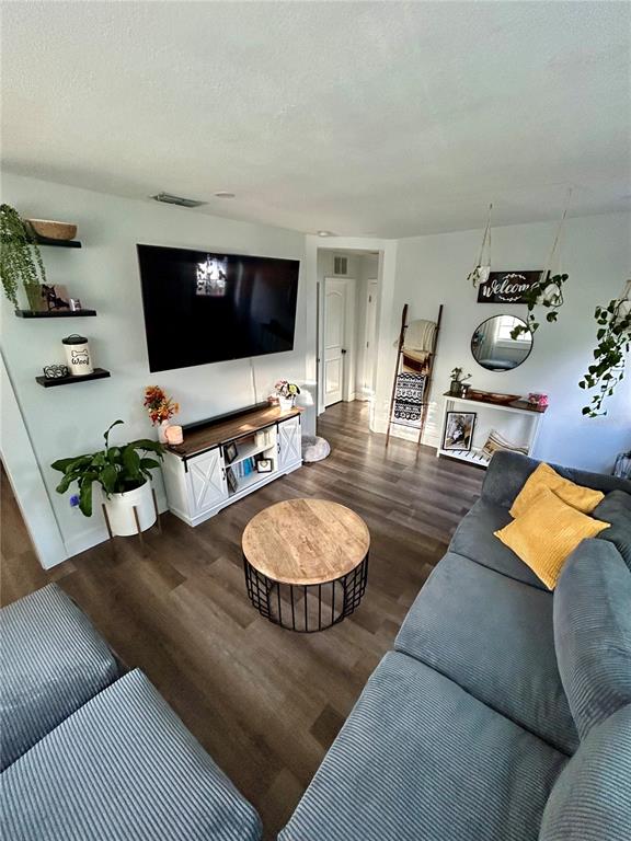 A living room features wood-look flooring, a wall-mounted television, a white media console, and a sofa — 3550 2ND AVENUE S, ST PETERSBURG, FL