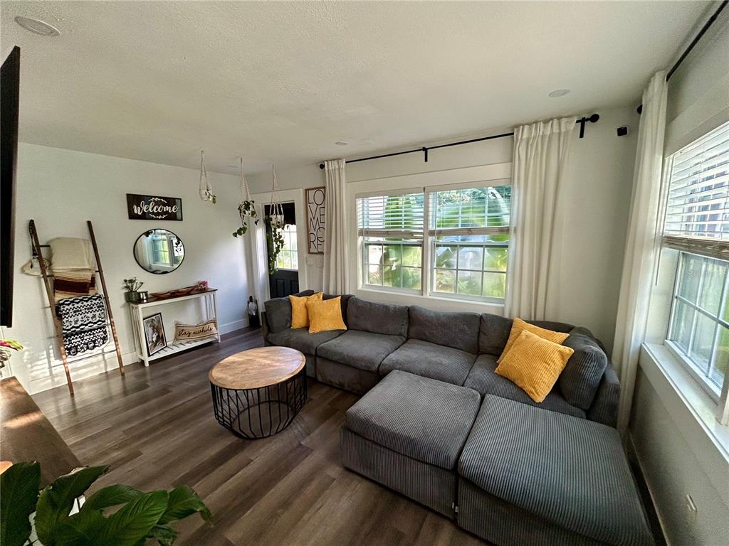 A living room features a gray sectional sofa, a round coffee table, and wood-look flooring — 3550 2ND AVENUE S, ST PETERSBURG, FL