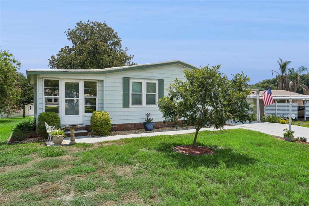 A single-story manufactured home with light siding, green shutters, and a front yard — 903 OLEANDER STREET, LADY LAKE, FL