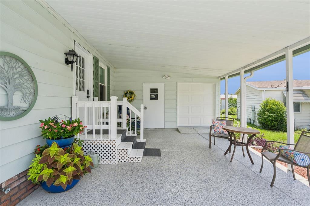 A covered patio features a concrete floor, white railings, a small table, and chairs — 903 OLEANDER STREET, LADY LAKE, FL