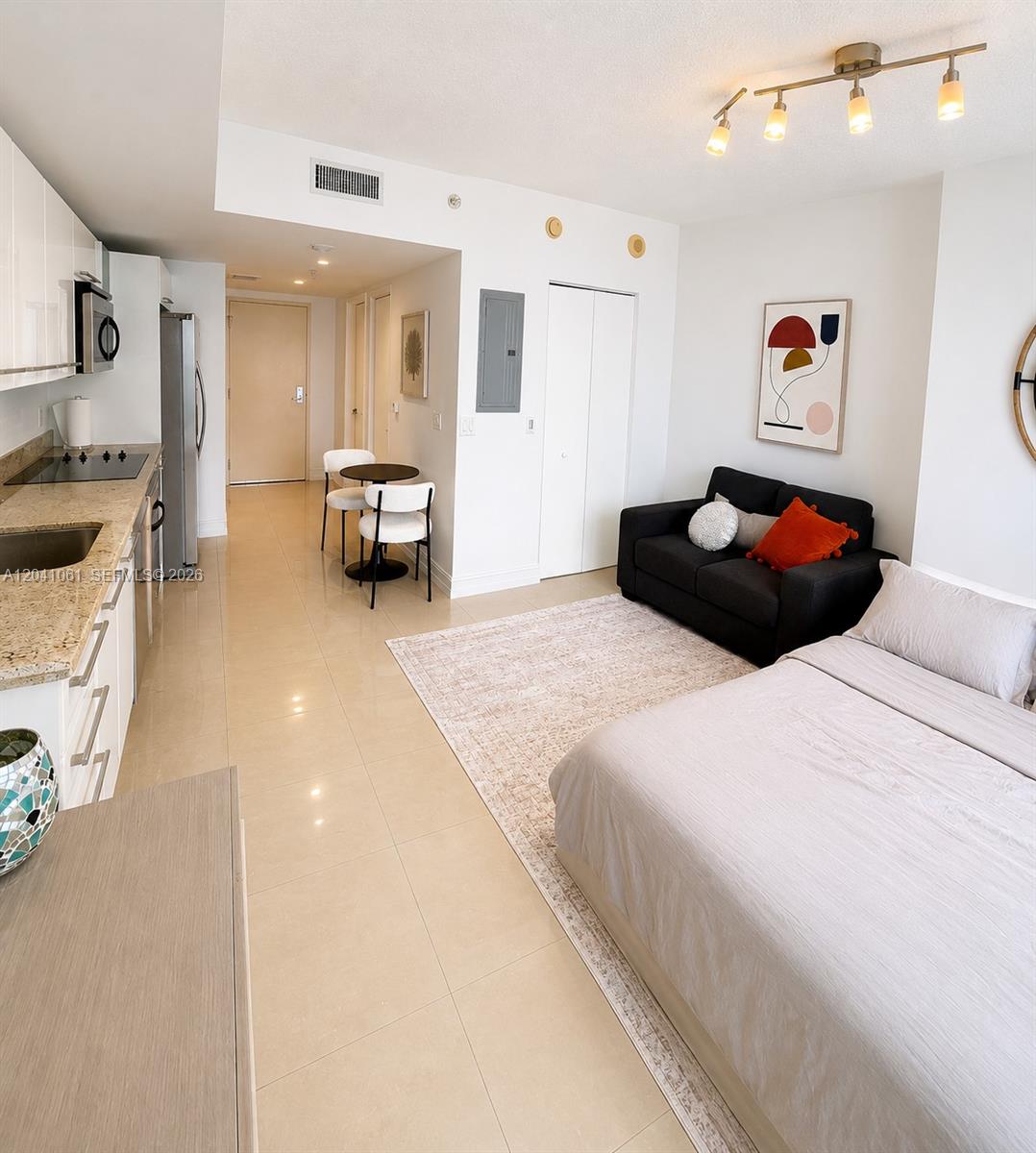 A studio apartment features a kitchen, dining area, sofa, and bed on tiled floors — 185 SW 7th St # 2706, Miami FL 33130, MIAMI, FL