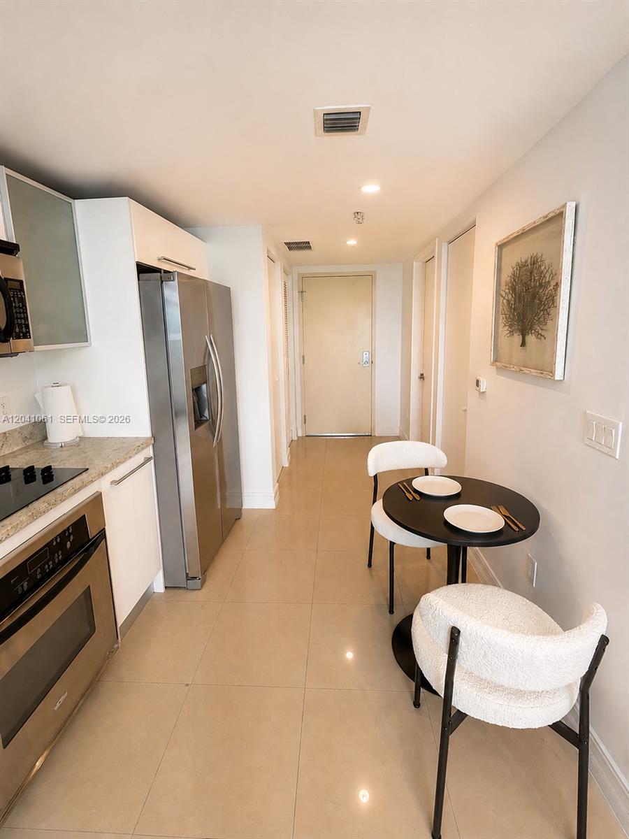 A kitchen features stainless steel appliances, light tile flooring, and a small round dining table — 185 SW 7th St # 2706, Miami FL 33130, MIAMI, FL