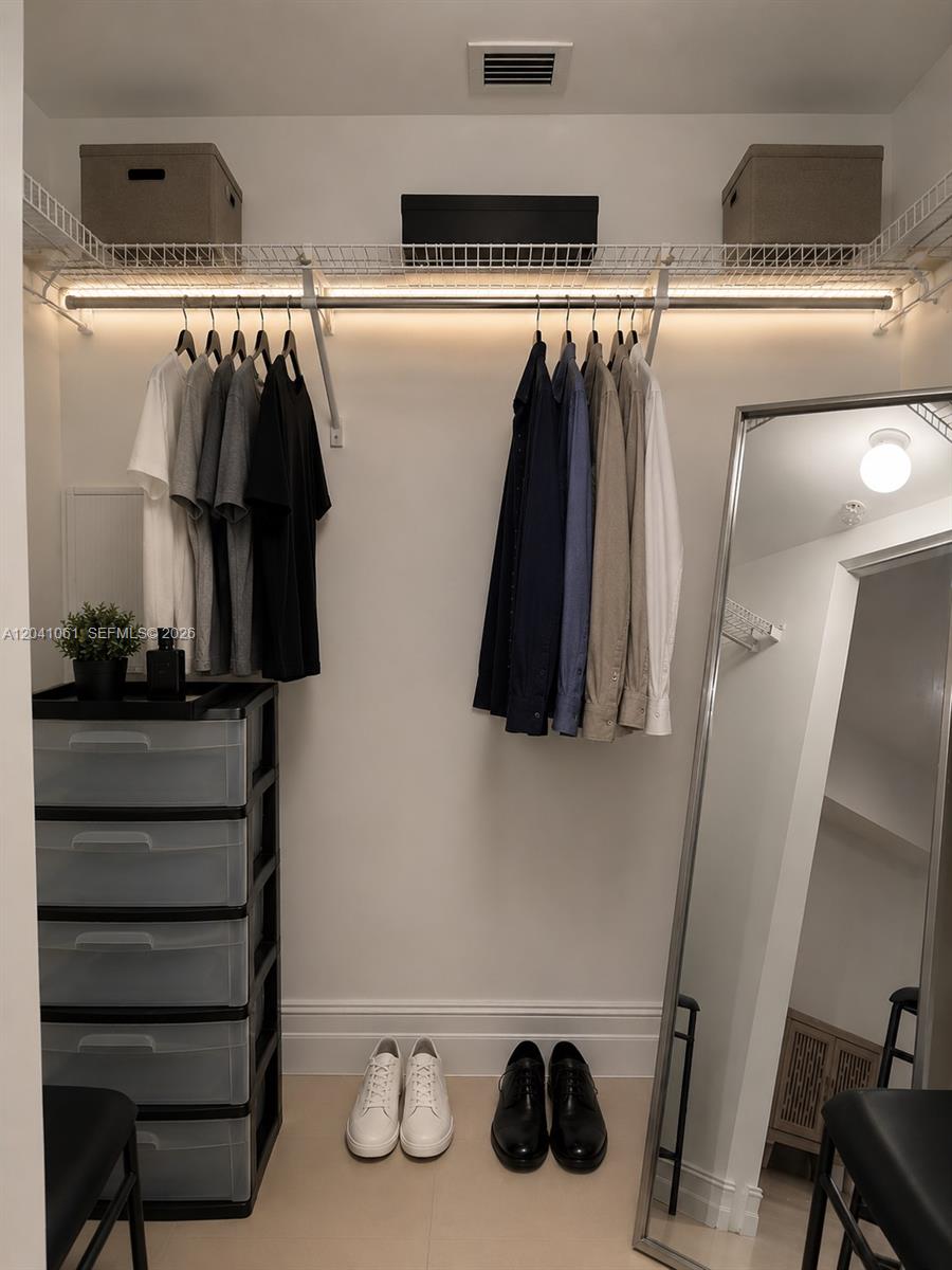 A walk-in closet features hanging clothes, a storage unit, and a floor-length mirror — 185 SW 7th St # 2706, Miami FL 33130, MIAMI, FL