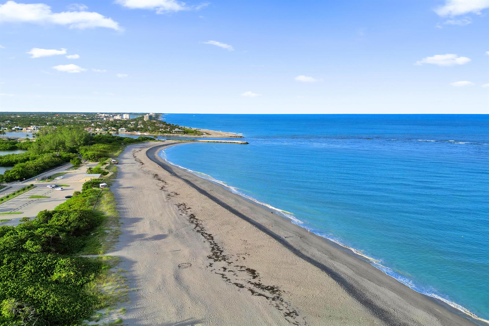 An aerial view shows a sandy beach, a parking lot, and a jetty along the ocean — 300 Ocean Trail Way # 410, Jupiter FL 33477, JUPITER, FL
