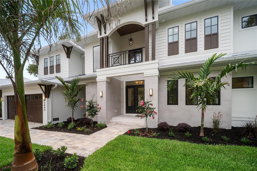 A two-story house with white siding, a covered balcony, and a paved walkway to the entrance — 3800 FLORES AVENUE, SARASOTA, FL