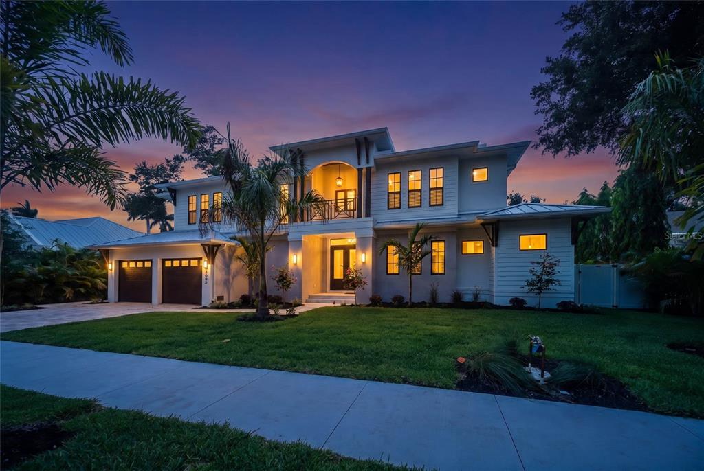 A two-story modern house with a two-car garage at dusk under a colorful sky — 3800 FLORES AVENUE, SARASOTA, FL