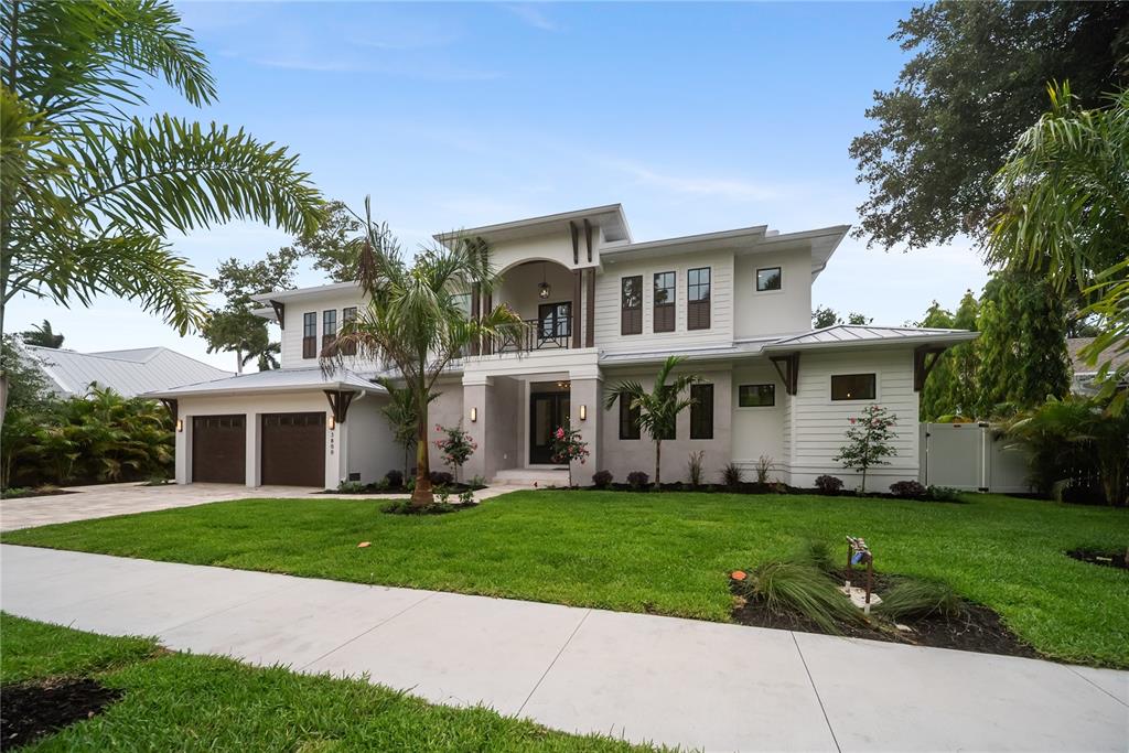 A two-story modern house with a white exterior, dark garage doors, and a palm-filled lawn — 3800 FLORES AVENUE, SARASOTA, FL