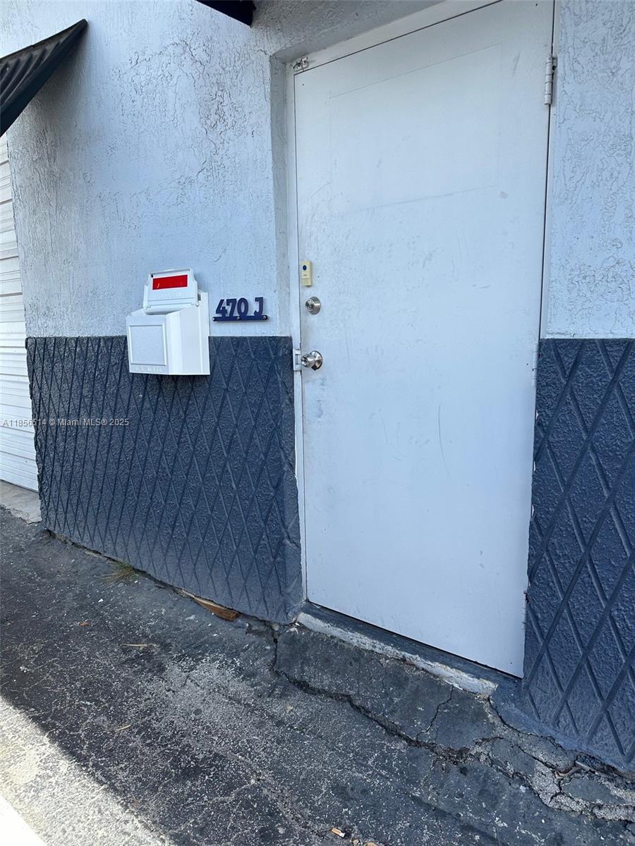 A white door with a mailbox and the number 470 J sits on a textured wall — 470 Ansin Blvd # 470J, Hallandale Beach FL 33009, HALLANDALE BEACH, FL