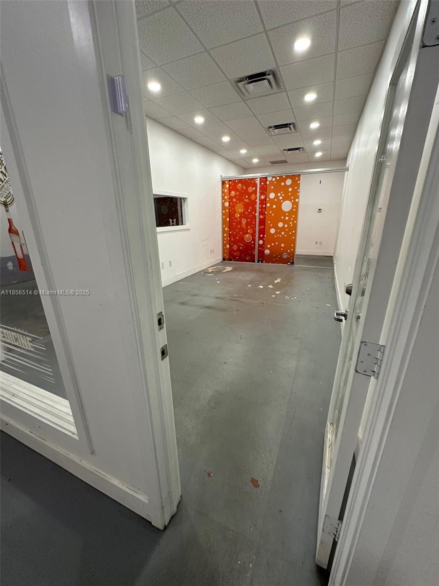 An empty office space features a gray concrete floor and orange patterned sliding glass doors — 470 Ansin Blvd # 470J, Hallandale Beach FL 33009, HALLANDALE BEACH, FL