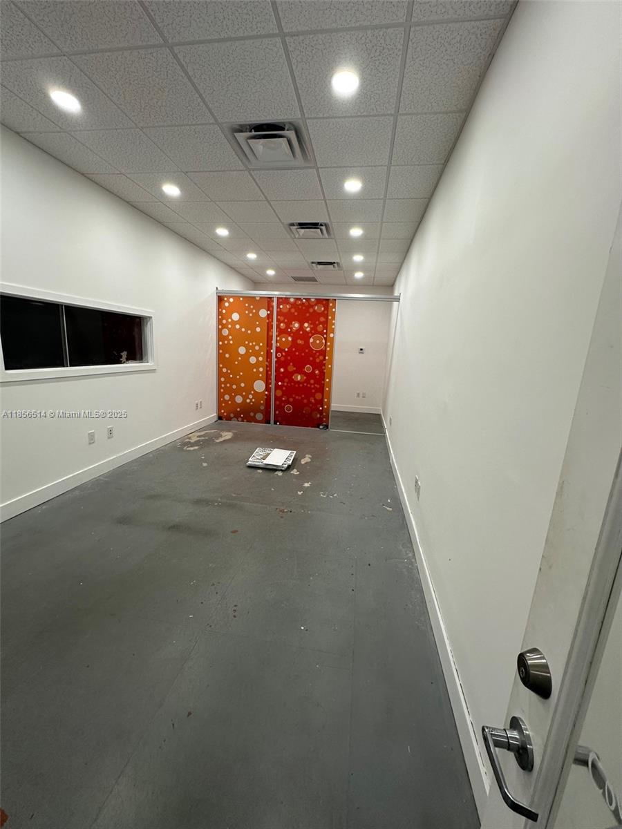 An empty rectangular room features white walls, a drop ceiling, and orange patterned sliding doors — 470 Ansin Blvd # 470J, Hallandale Beach FL 33009, HALLANDALE BEACH, FL