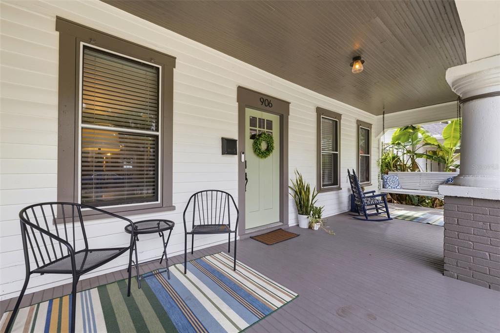 A covered front porch features white siding, a light green door, and outdoor furniture — 906 E PATTERSON STREET, TAMPA, FL