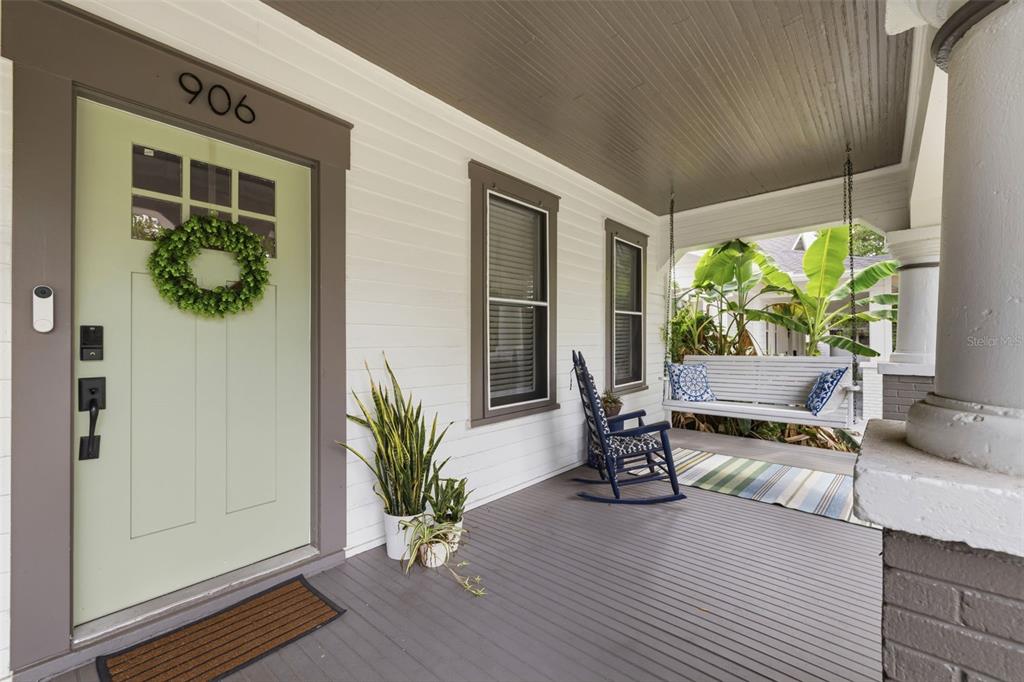 A covered front porch features a light green door, a hanging bench, and a rocking chair — 906 E PATTERSON STREET, TAMPA, FL