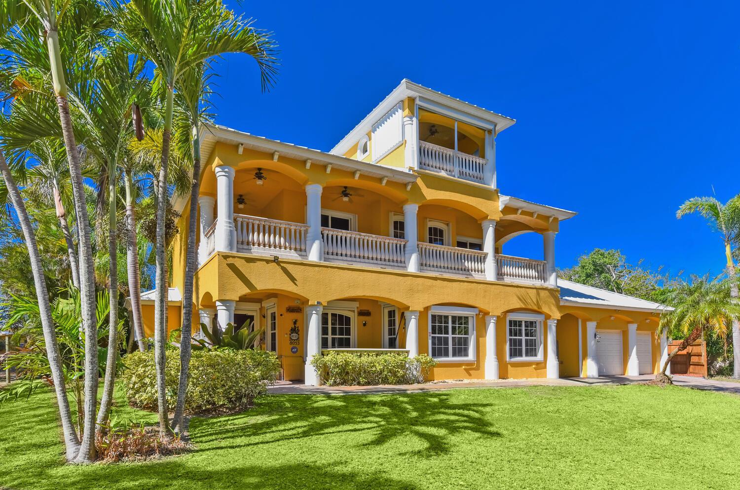 A three-story yellow house with white columns, balconies, and a palm-lined front lawn — 8053 S Indian River Drive, Fort Pierce FL 34982, FORT PIERCE, FL
