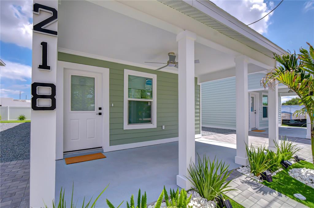 A covered front porch with green siding, a white door, and a house number pillar — 218 8TH AVENUE DRIVE W, BRADENTON, FL