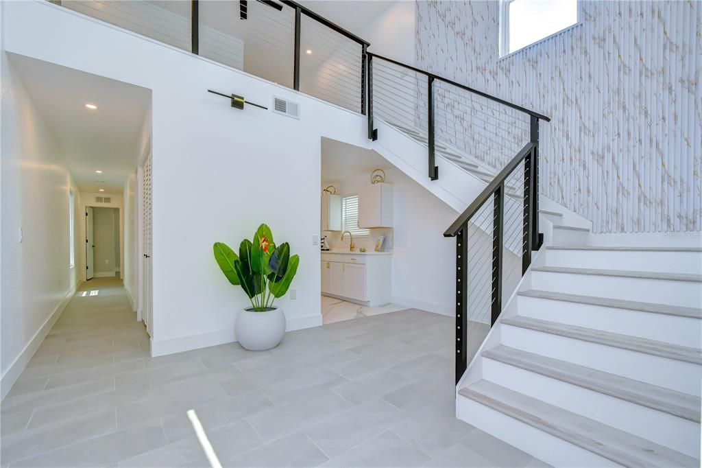 A bright entryway features a staircase with cable railings, light tile flooring, and a potted plant — 218 8TH AVENUE DRIVE W, BRADENTON, FL