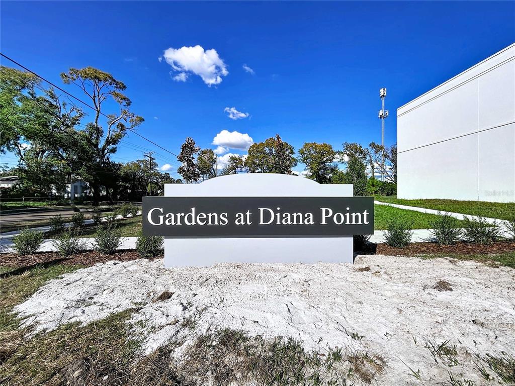 A white monument sign for Gardens at Diana Point stands on a dirt patch — 4370 CAMBIO GARDENS COURT, TAMPA, FL