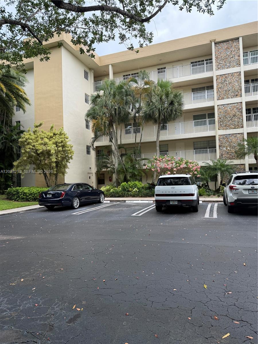 A multi-story apartment building exterior with a parking lot and palm trees in front — POMPANO BEACH, FL