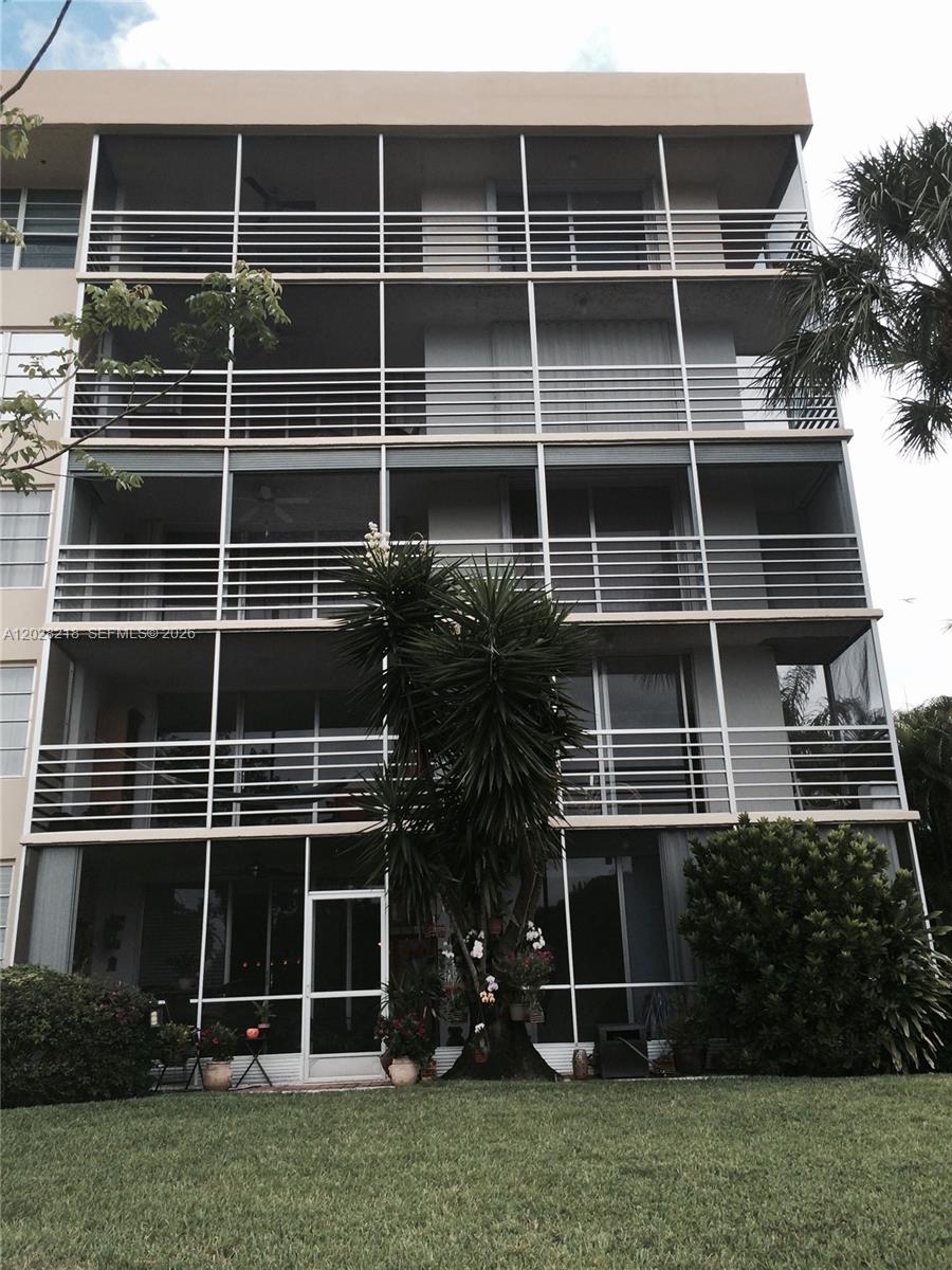 The exterior of a multi-story apartment building features screened balconies and a landscaped lawn — POMPANO BEACH, FL