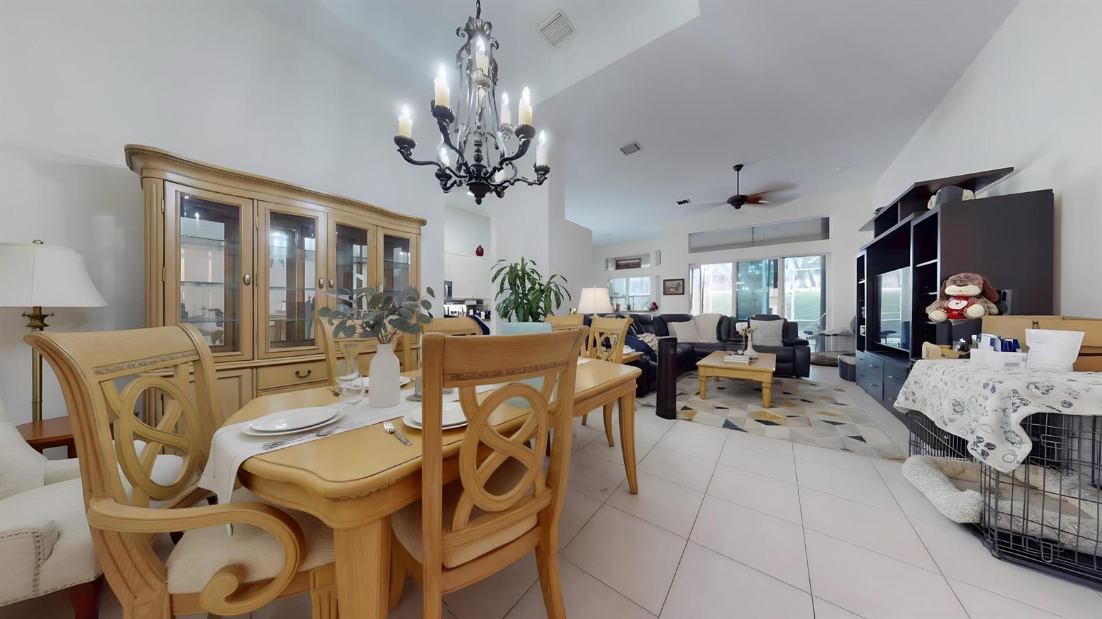 A dining area with a wooden table and chandelier opens into a living room — 10072 Armani Drive, Boynton Beach FL 33437, BOYNTON BEACH, FL
