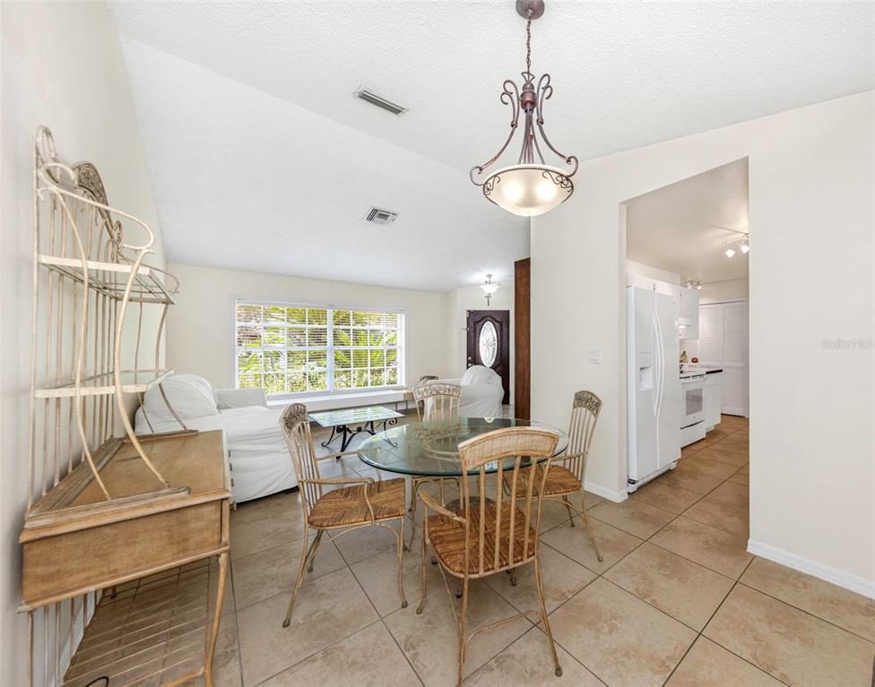 A dining area with a glass table and chairs sits adjacent to a kitchen and living room — 2437 HAWK AVENUE, PALM HARBOR, FL