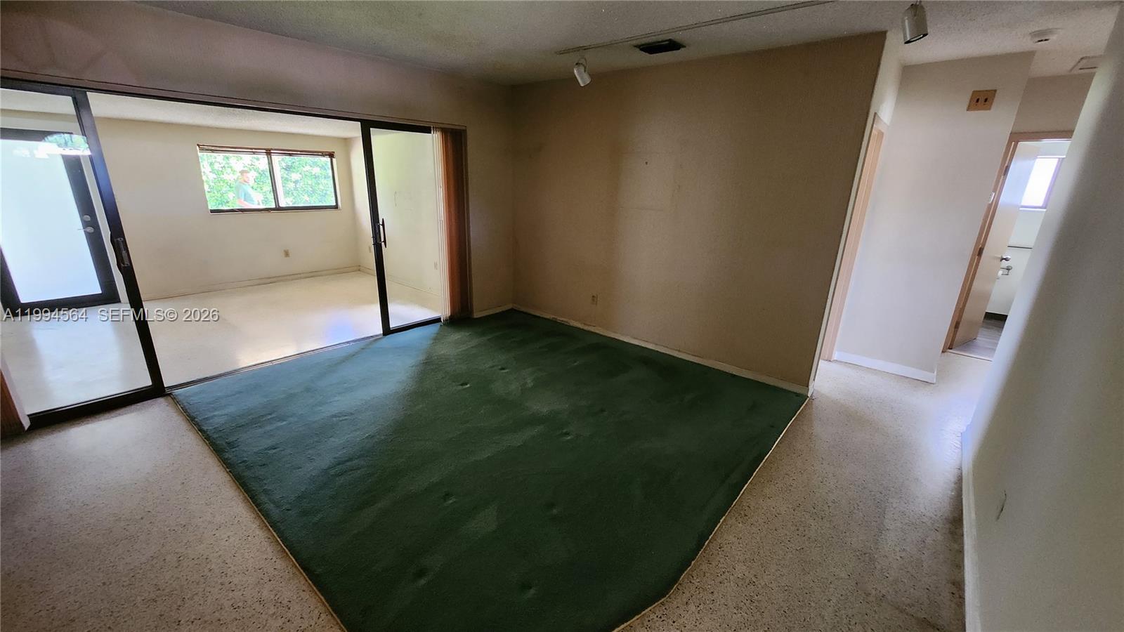 A room with a green carpet area, sliding glass doors, and a tiled floor — 6241 NW 110th St, Hialeah FL 33012, HIALEAH, FL
