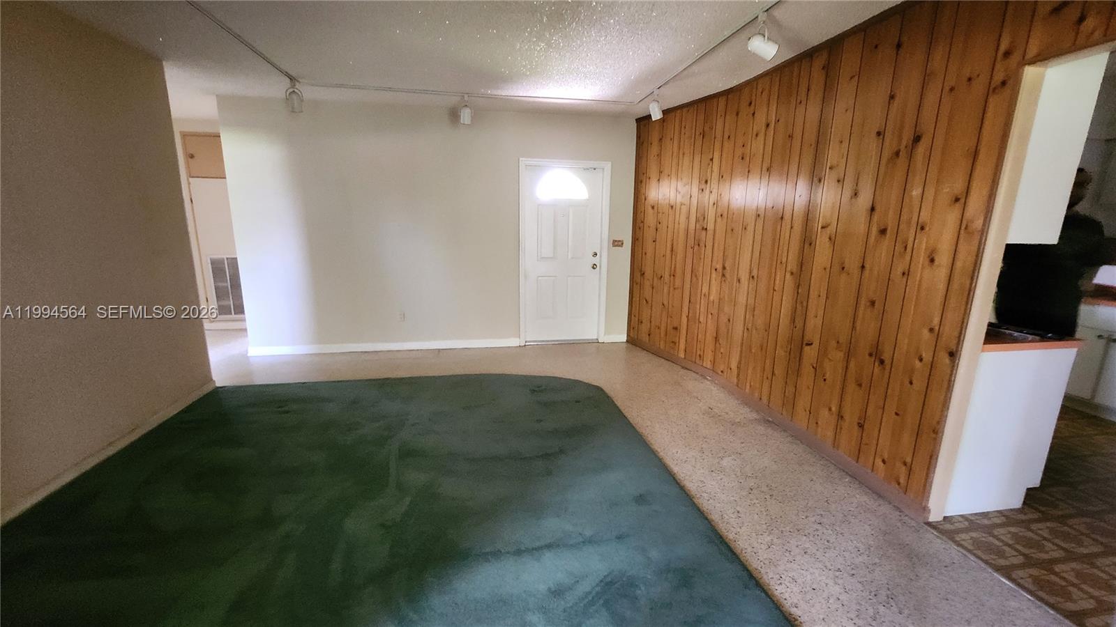 A room features green carpeting, a wood-paneled wall, and a white entry door — 6241 NW 110th St, Hialeah FL 33012, HIALEAH, FL