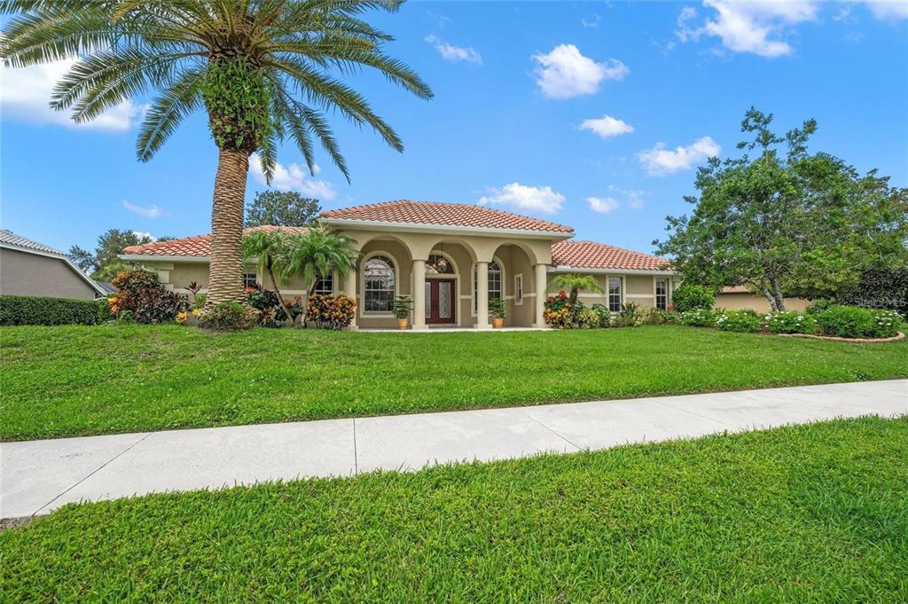 A single-story house with a tile roof, arched entryway, and a palm tree in front — 8356 MAREVA LANE, SARASOTA, FL