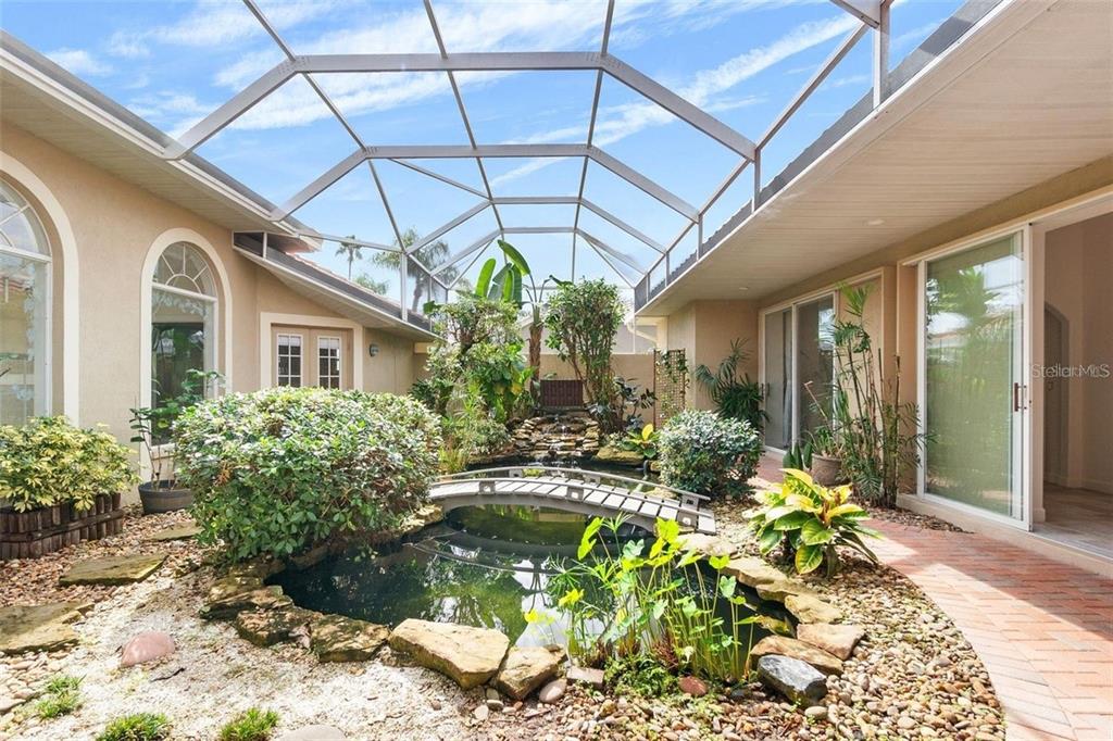 An enclosed courtyard features a koi pond with a small bridge and lush landscaping — 8356 MAREVA LANE, SARASOTA, FL