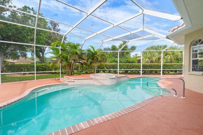 A screened-in swimming pool and hot tub are set on a terracotta-colored patio — 8356 MAREVA LANE, SARASOTA, FL