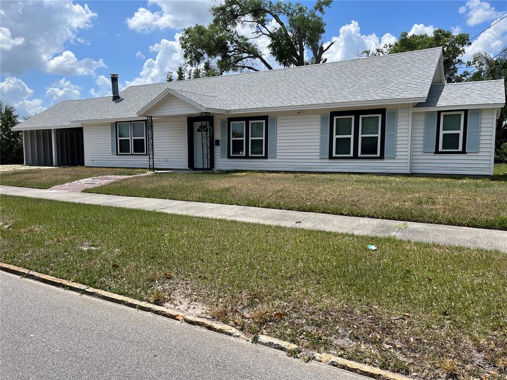 A single-story white house with a gray shingled roof and a carport sits behind a lawn — 521 OHIO STREET, WINTER PARK, FL