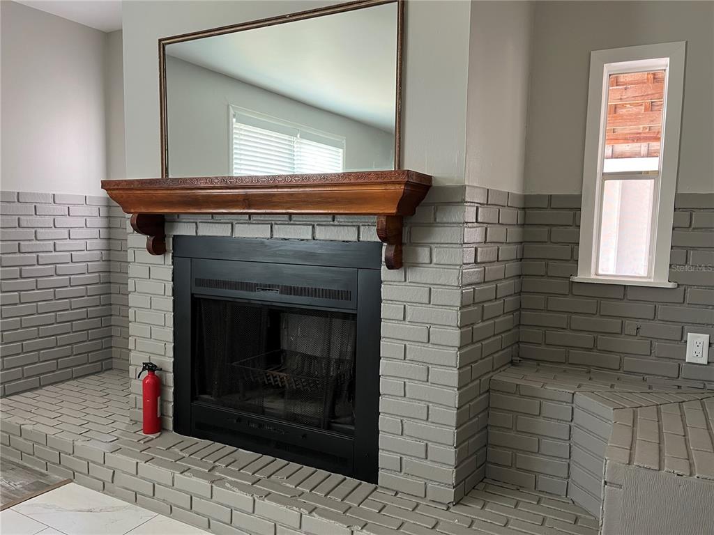 A gray painted brick fireplace features a wooden mantel and a large rectangular mirror above — 521 OHIO STREET, WINTER PARK, FL