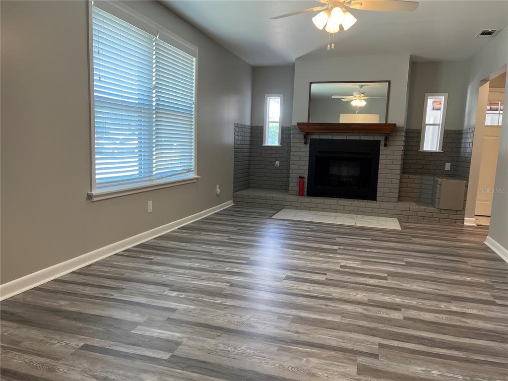 A living room features gray walls, wood-look flooring, and a brick fireplace with a mantel — 521 OHIO STREET, WINTER PARK, FL
