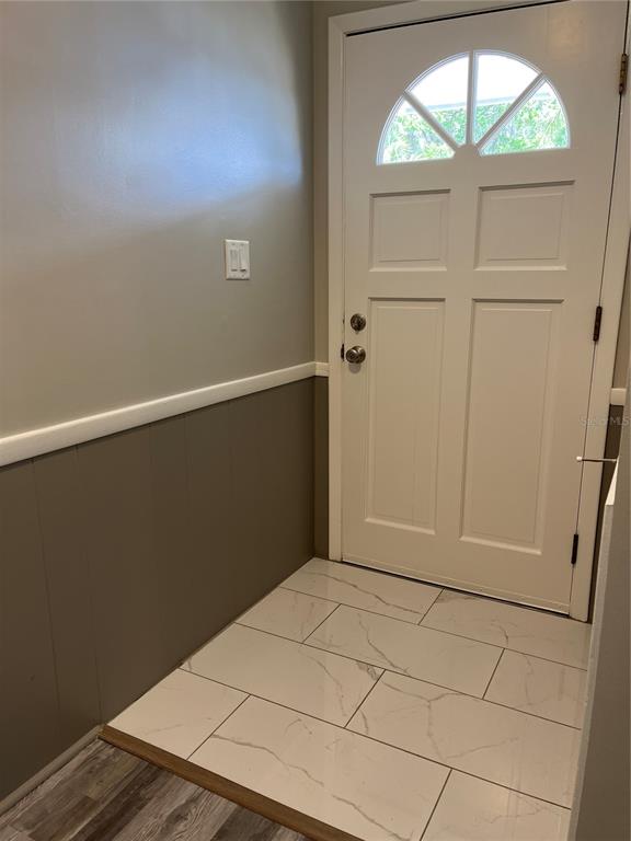 An entryway features a white front door, gray paneled walls, and white marble-look floor tiles — 521 OHIO STREET, WINTER PARK, FL