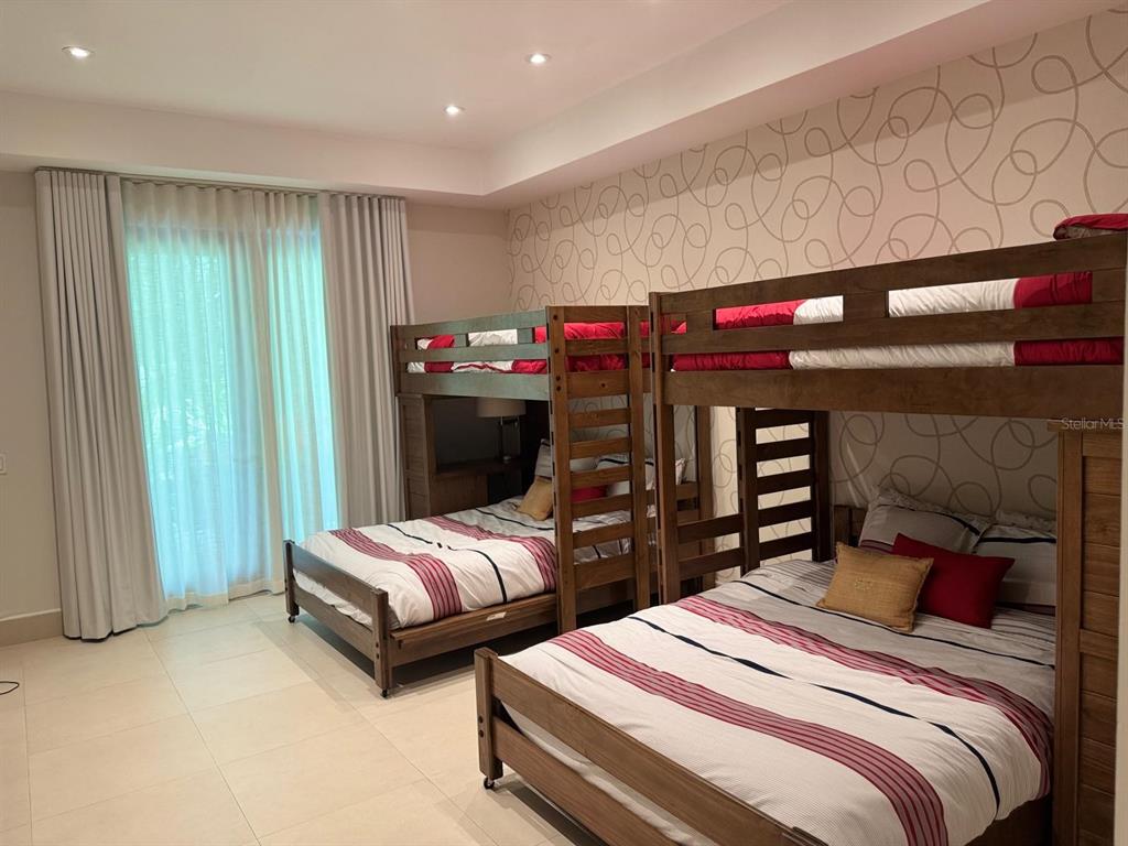 A bedroom features two wooden bunk beds with striped bedding against a patterned accent wall — 7000 BAHIA BEACH BLVD, RIO GRANDE, PR