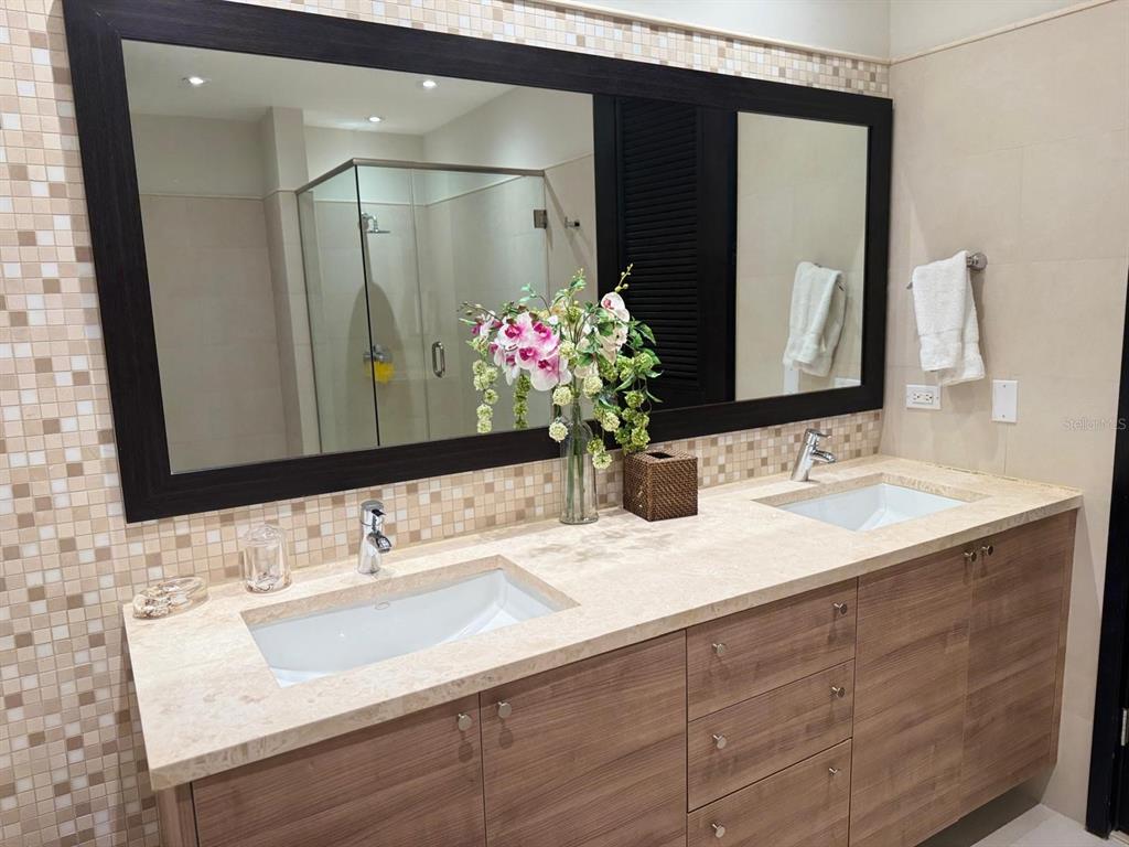 A bathroom features a double vanity with a stone countertop, wood cabinets, and a large mirror — 7000 BAHIA BEACH BLVD, RIO GRANDE, PR
