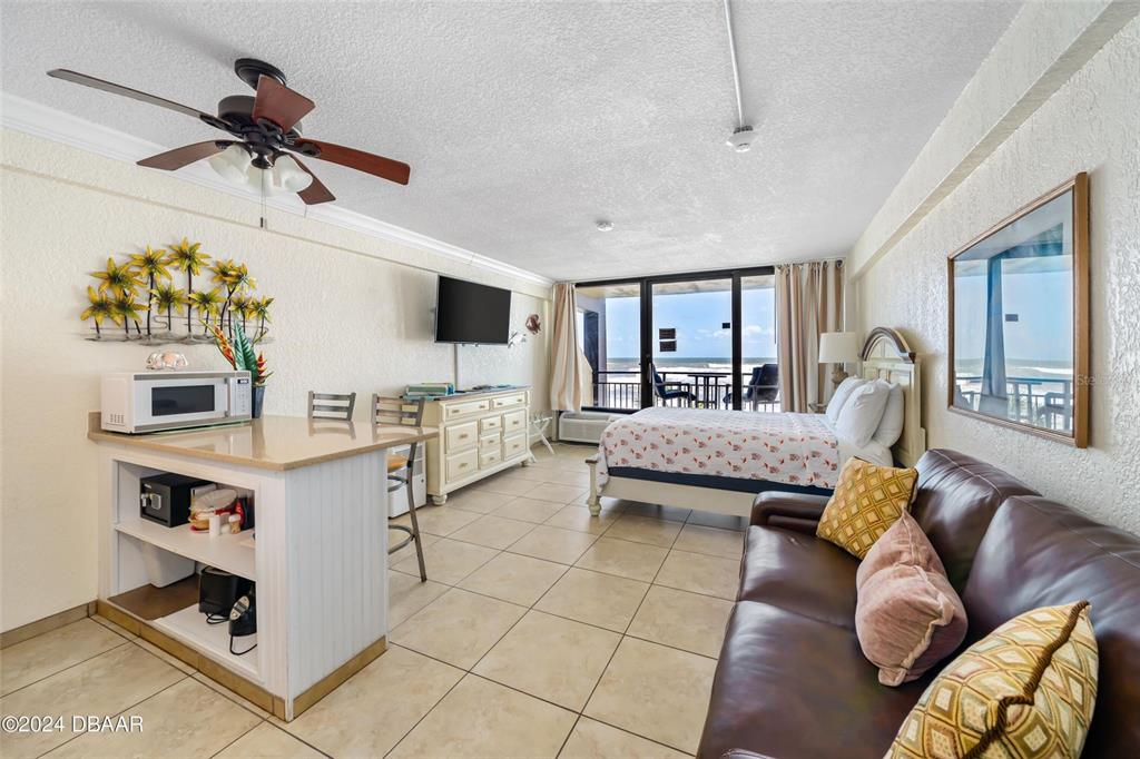 A studio apartment features a kitchenette, a bed, a leather sofa, and an ocean view — 2301 S ATLANTIC AVENUE UNIT 236, DAYTONA BEACH, FL