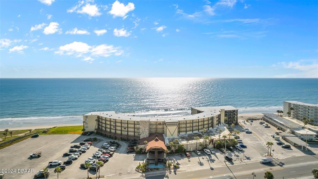 An aerial view shows a curved beachfront hotel with a large parking lot — 2301 S ATLANTIC AVENUE UNIT 236, DAYTONA BEACH, FL