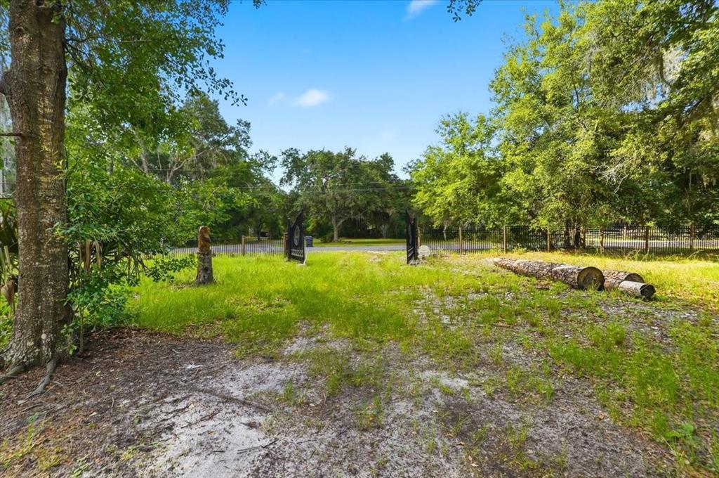 A grassy, wooded lot features a gated entrance and a fallen log in the foreground — 1425 PIONEER DRIVE, LAKELAND, FL