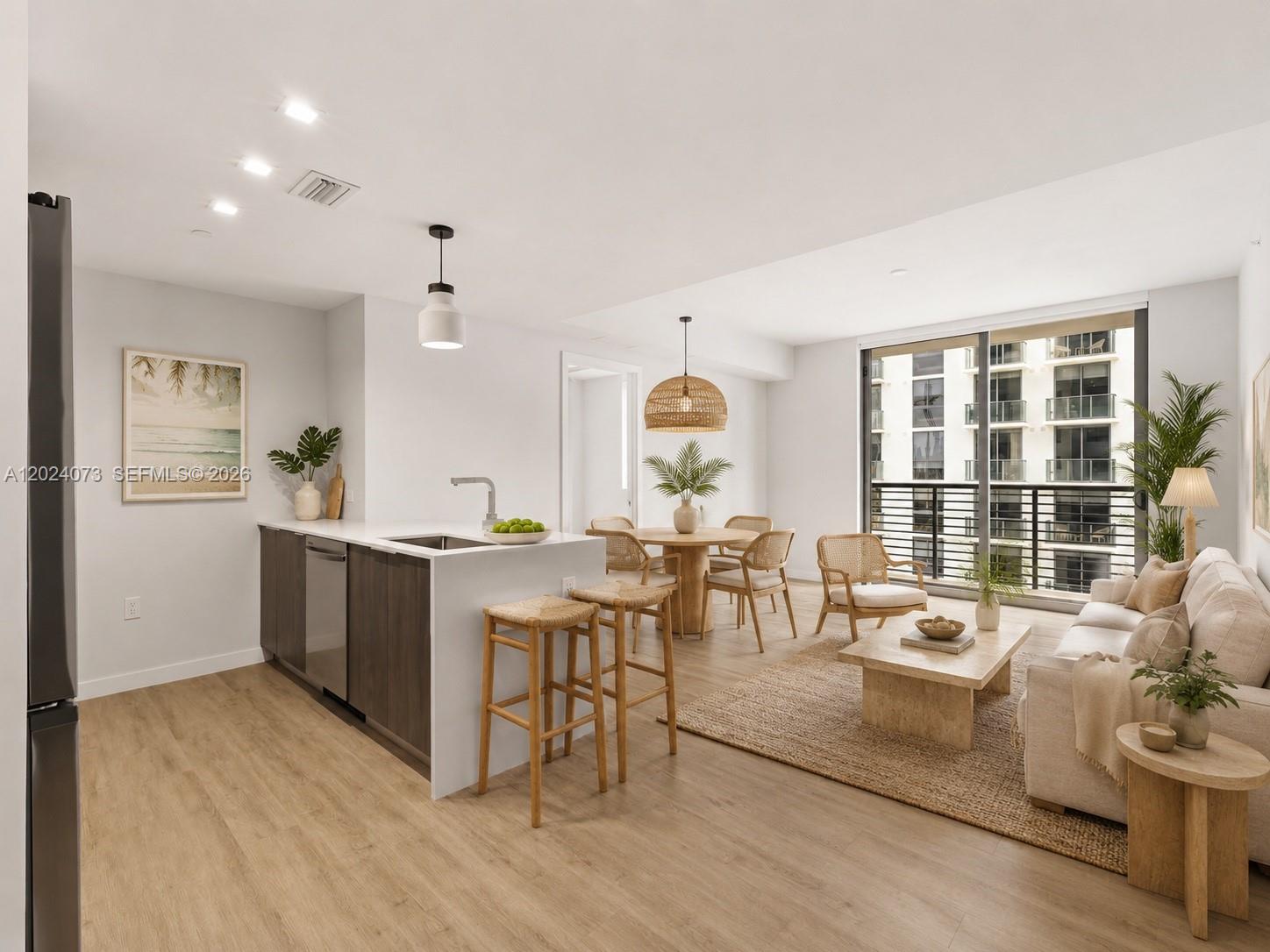 An open-concept living and dining area features a kitchen island, light wood floors, and balcony — 697 N Miami Ave # 1810, Miami FL 33136, MIAMI, FL