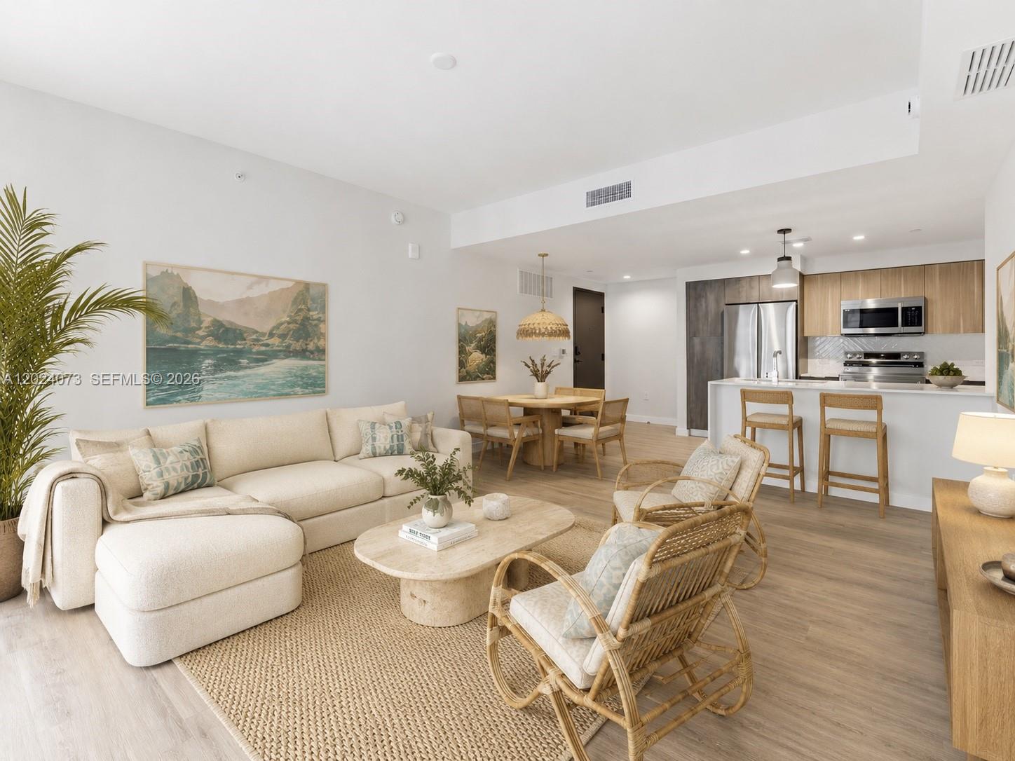 An open-concept living and dining area features a sectional sofa, rattan chairs, and kitchen island — 697 N Miami Ave # 1810, Miami FL 33136, MIAMI, FL