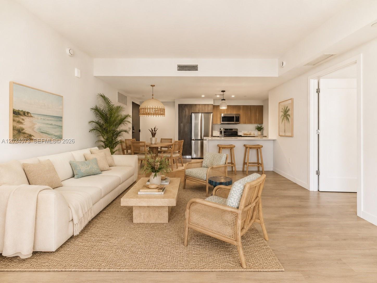 This open-concept living area features a neutral sofa, rattan armchairs, and a modern kitchen — 697 N Miami Ave # 1810, Miami FL 33136, MIAMI, FL