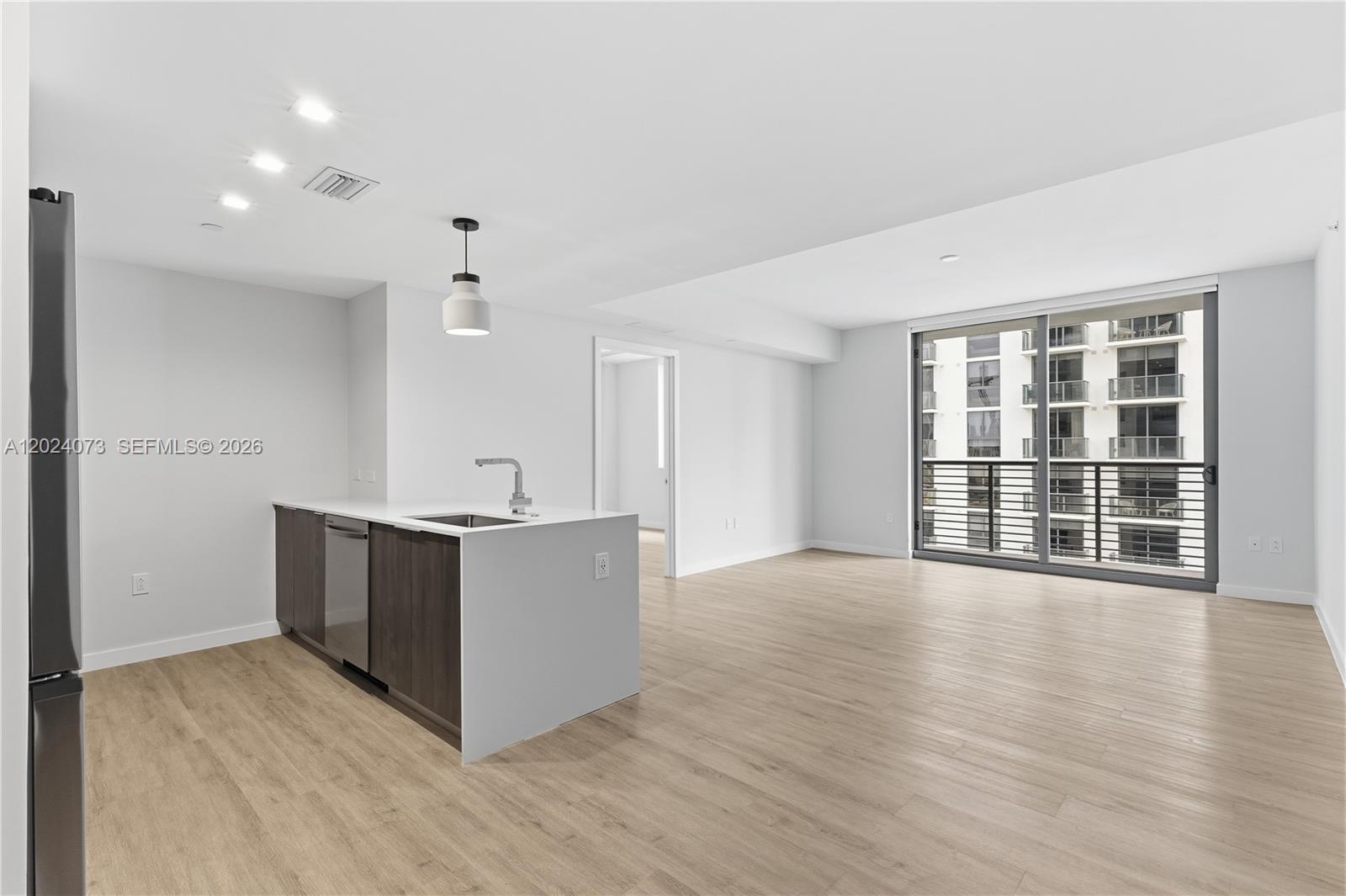 A modern kitchen island with a sink sits in an open-plan living area — 697 N Miami Ave # 1810, Miami FL 33136, MIAMI, FL